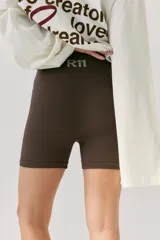 Biker deportiva de tejido seamless color marrón oscuro, con cintura alta ancha y logo R11 estampado en la parte trasera.