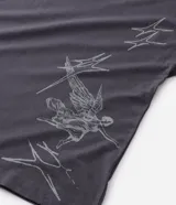 Remera de corte oversized color gris oscuro, con cuello redondo y manga corta. Presenta una estampa gráfica en la espalda que incluye un ángel, estrellas y el lettering 'No Mercy' junto a la frase 'Las calles no perdonan'.