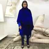 Capa azul de lana merino afieltrada, con guarda tejida en cuello y ruedo. Se puede usar como poncho o como capa abierta.