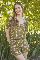 Conjunto de pijama verde oliva con estampado de flores lilas, compuesto por un top de mangas cortas con escote en V y un short con cintura elástica y volados en el ruedo.