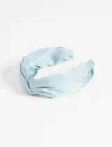 Vincha rígida celeste con tela fruncida y pequeños brillos plateados.