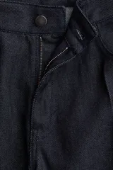 Jean de cinco bolsillos en denim de algodón crudo, con cintura estándar, cierre y botón. Presenta piernas rectas con pliegues cosidos en la parte delantera.