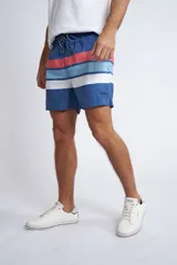 Short de baño con cintura elástica y cordón ajustable, confeccionado en tela ligera de secado rápido. Presenta un estampado botánico integral en tonos amarillos, blancos y azules, con dos bolsillos delanteros y uno posterior.