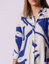 Camisa de manga larga con estampado abstracto en tonos verde y blanco. Cuello con solapa y abertura central con botones. Largo de manga regulable con presilla y botón. Terminación de ruedo anudada opcional.