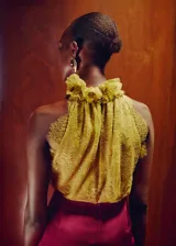Top amarillo de encaje sin mangas, con cuello gorguera alto y cierre de botones en el cuello. Cuenta con forro interior y diseño entallado.