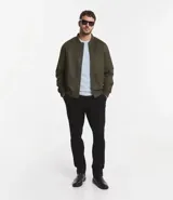 Chaqueta bomber azul marino lisa, con cierre frontal, cuello redondo y bolsillos laterales.