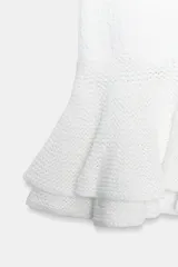 Minifalda blanca de punto con cintura elástica y diseño con volantes en el bajo.