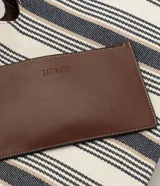 Cartera shopper de algodón con diseño a rayas en tonos neutros y detalles de ribetes y asas de hombro en PU marrón. Cuenta con una abertura central pronunciada y gran capacidad de almacenamiento.