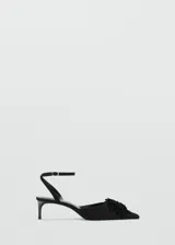 Zapato de tacón kitten color negro, con punta fina, tira ajustable al tobillo con hebilla y detalle de aplicación floral con flecos en el empeine.