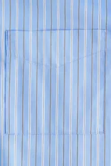 Camisa oversize de popelina a rayas celestes y blancas, con cuello clásico, mangas largas, bolsillos en el pecho y cierre frontal de botones.
