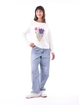 Remera de manga larga color azul, con cuello redondo y un estampado central de flores en tonos pastel sobre un recuadro gris claro.