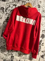 Canguro rojo con capucha y cordones ajustables. Estampado en la espalda con la palabra "NEKOMA" en letras blancas.