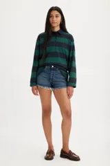 Short de denim de tiro bajo para mujer, confeccionado en algodón con baja elasticidad. Presenta un lavado azul medio con efecto desgastado, diseño de cinco bolsillos y dobladillo deshilachado con flecos.