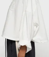 Camisa blanca de sarga de algodón orgánico con corte oversize y bajo redondeado. Presenta cuello abotonado, mangas enrolladas y el número "10" bordado en el pecho.