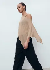 Poncho de tejido ligero y traslúcido en color beige, con diseño asimétrico y corte holgado.