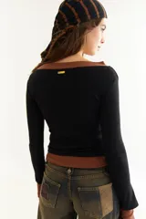 Top de manga larga con diseño de doble capa superpuesta, combinando una capa superior negra y una inferior marrón. Presenta cuello redondo, ajuste al cuerpo y detalle de bordado BG en la parte inferior.