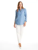 Blusa de lyocell color azul con efecto denim, cuello camisero con solapa y escote en V con cierre de un botón. Presenta mangas largas con terminación doblada y ruedo redondeado.