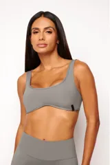 Top deportivo color gris, con escote cuadrado y curvatura frontal que realza la silueta. Confeccionado en poliamida con ajuste slim, incluye forro interno y apertura para almohadillas removibles.