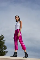 Pantalón de tiro alto confeccionado en bengalina engomada con acabado metálico brillante. Presenta un corte capri semi oxford con costura horizontal a la altura de la rodilla, cierre frontal con botón metálico y bolsillos funcionales.