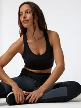 Top deportivo negro con cortes y pespuntes inspirados en la época victoriana y diseño de estética corsetera, que ofrece sujeción alta.