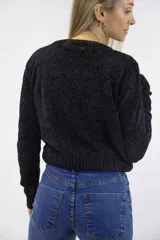 Buzo tejido de chenille blanco con cuello redondo, mangas largas, terminaciones acanaladas y diseño frontal con detalles de trenzas y texturas combinadas.
