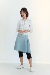 Falda midi de denim en tono azul claro, con tiro medio y diseño asimétrico con tablas laterales. Cuenta con cierre lateral mediante cremallera metálica.