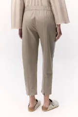 Pantalón estilo chino color beige con elástico en la cintura y cierre metálico en la pierna. Cuenta con bolsillos laterales con cierre invisible.