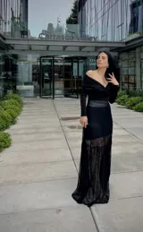 Blusa negra con escote off-shoulder y mangas largas ajustadas.