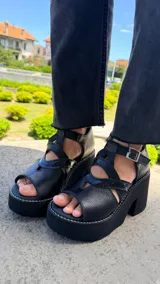 Sandalias de cuero negro con plataforma y taco ancho, diseño de tiras cruzadas y cierre de hebilla en el tobillo.