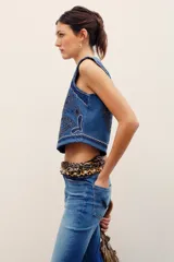 Chaleco de denim azul de corte ajustado, con cuello en V y elaborados bordados decorativos en contraste.