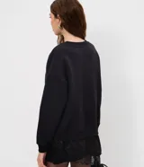 Buzo de algodón con felpa, corte oversized, cuello redondo y mangas largas. Presenta un detalle de encaje aplicado en el ruedo, aportando un contraste femenino y sofisticado.