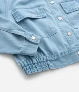 Campera de jean celeste de algodón con cuello inglés, abotonada, de manga larga ajustada con elástico en la cintura.