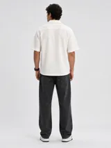 Camisa de manga corta color blanco, de corte holgado y tejido texturizado con cierre frontal de botones.