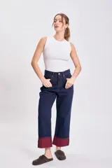 Pantalón de jean azul oscuro, de corte recto y holgado, con el bajo doblado mostrando un forro color bordó.