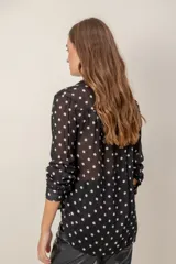 Camisa de manga larga con estampado de leopardo, cuello clásico y cierre frontal de botones. Presenta un corte holgado y puños abotonados.