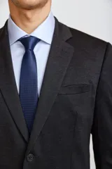 Ambo de corte slim compuesto por saco de dos botones y pantalón de vestir a juego, en color azul marino. El saco presenta solapas clásicas, bolsillos laterales con solapa y bolsillo en el pecho con pañuelo decorativo.