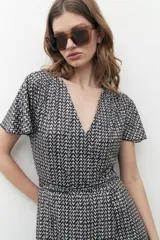 Vestido midi con estampado geométrico en blanco y negro, corte cruzado, mangas cortas y escote en V.