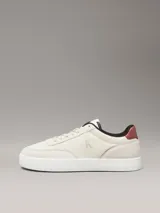 Zapatillas de corte bajo Calvin Klein Jeans en color beige, confeccionadas en una combinación de ante y piel nobuck. Presentan un diseño minimalista con suela cupsole blanca, detalle de trabilla trasera en color marrón y forro interior en contraste negro. Incluye el logo de la marca grabado en el lateral y en la mediasuela.