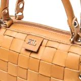 Cartera tipo baúl color suela, confeccionada en cuero con diseño tejido. Tiene asas fijas y correa larga desmontable para usar al hombro. Cuenta con bolsillo externo con cierre y bolsillo interno con cierre.