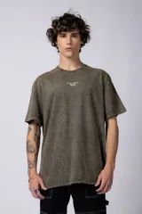 Remera de manga corta, corte holgado, color verde oliva con efecto acid wash. Presenta un pequeño estampado blanco en el pecho con el texto "ASTRAL ENERGY" y un símbolo gráfico debajo.