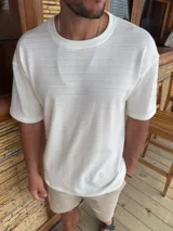 Remera de corte oversize color blanco, confeccionada en tejido de punto con textura acanalada, cuello redondo y mangas cortas.