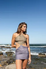 Vestido corto de estilo cut-out con escote halter, confeccionado en lycra ecofriendly con estampado geométrico en tonos verdes y azules.