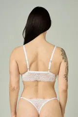 Conjunto de lencería de encaje blanco, compuesto por un top triangular sin broche con breteles regulables y una tanga regulable con diseño colaless.
