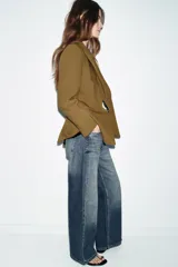 Blazer entallada de cuello solapa y manga larga con hombreras. Presenta bolsillos delanteros de vivo y cierre frontal con un botón metálico decorativo.
