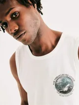 Musculosa blanca de corte clásico con cuello redondo y estampa circular en el pecho que representa un faro en medio de una tormenta con la frase 'Sail through the storm'.