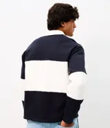 Buzo masculino confeccionado en algodón con felpa y diseño de bloques rayados en color azul marino y blanco. Presenta cuello polo, cierre frontal parcial con botones, manga larga y estampa frontal con íconos y texto.