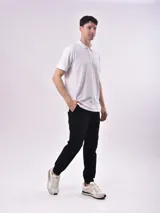 Remera tipo chomba de manga corta, color negro, con cuello y tapeta de botones. Presenta un pequeño logo bordado en el pecho.