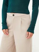 Pantalón de vestir color beige, de corte recto y tiro alto, con cierre frontal de botón y pinzas en la cintura.