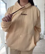 Canguro deportivo de tela suave con logo bordado, diseño holgado y mangas largas.