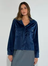 Chaqueta azul marino de terciopelo con cuello camisero, cierre frontal con botones, dos bolsillos de parche con solapa y mangas largas con puños abotonados.